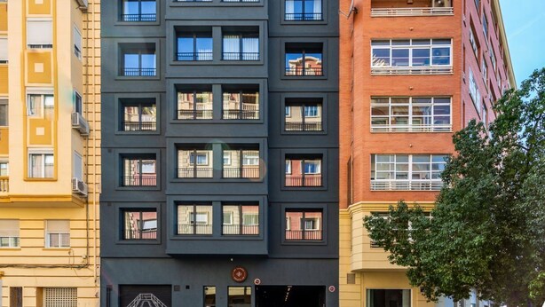 Un immeuble à plusieurs étages doté d’une architecture moderne, caractérisé par un mélange de styles de fenêtres et de balcons.