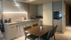 Une cuisine moderne dotée d’un îlot central, d’appareils électroménagers intégrés et d’un coin repas avec une table et des chaises.