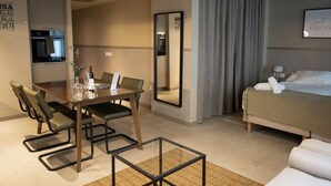 A hotel room with a bed, a dining table with chairs, a kitchen area, and a large mirror. - STANDARD APARTMENT IN VALENCIA (València)