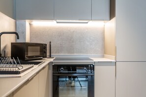 A compact kitchen with a microwave, oven, and a built-in stove. - APARTMENT WITH TERRACE IN VALENCIA (València)