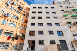 A multi-story building with balconies, air conditioning units, and a visible entrance.