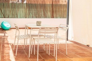 A patio with white metal chairs and a table, a stone sculpture, and a green object on the floor. - APARTMENT WITH TERRACE IN VALENCIA (València)