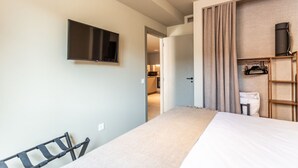 Ett hotellrum med en säng, en tv som är monterad på väggen, en garderob och en dörr som leder till ett badrum.