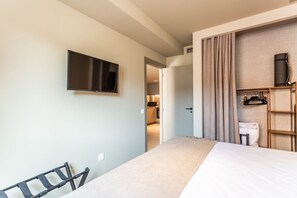 Une chambre d’hôtel comprenant un lit, un téléviseur fixé au mur, une armoire et une porte donnant accès à une salle de bain.