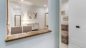 A modern hotel room with a wooden console table, a sofa, a cabinet, and a large mirror. - CIANCALEONI APPARTAMENTO (Rome)