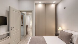 A bedroom with a bed, a TV, a wardrobe, and a nightstand with a lamp. - CIANCALEONI APPARTAMENTO (Rome)