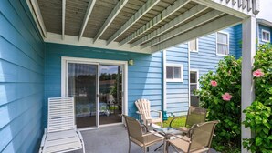 A covered patio with a sliding glass door, outdoor furniture, and a blue house. - Villas at Island Club Community, Pools, Jacuzzi and More! (Kissimmee)