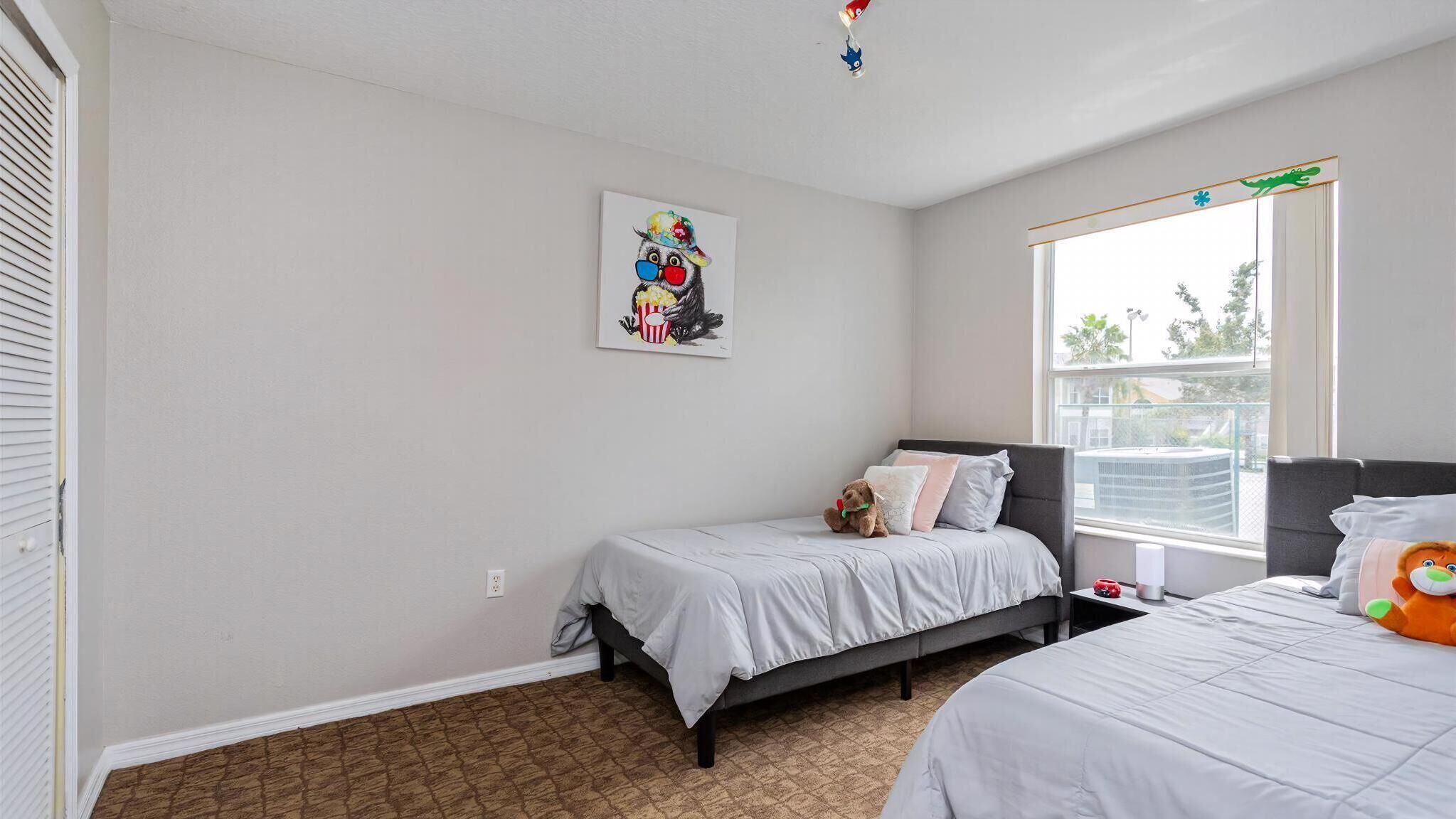 Un dormitorio con dos camas, una ventana con vistas y un cuadro en la pared.