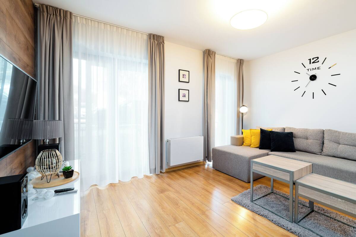 Una sala de estar moderna con un sofá, una mesa de centro, un televisor y un reloj de pared.
