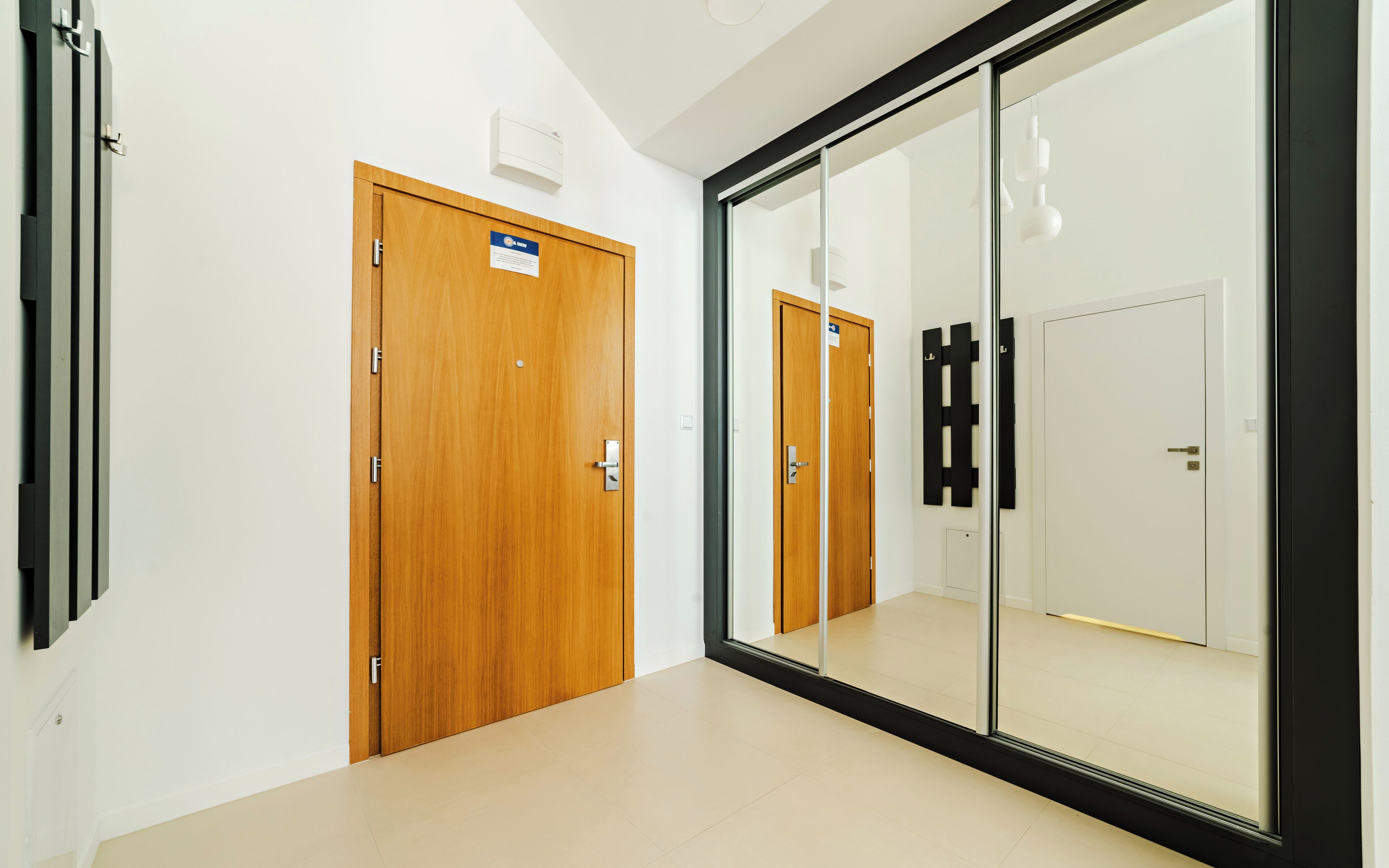 Un couloir avec des portes en bois et une cloison en verre.