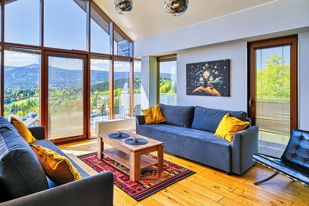 Un salón amplio con ventanas grandes, un sofá, una mesa de centro y una silla.