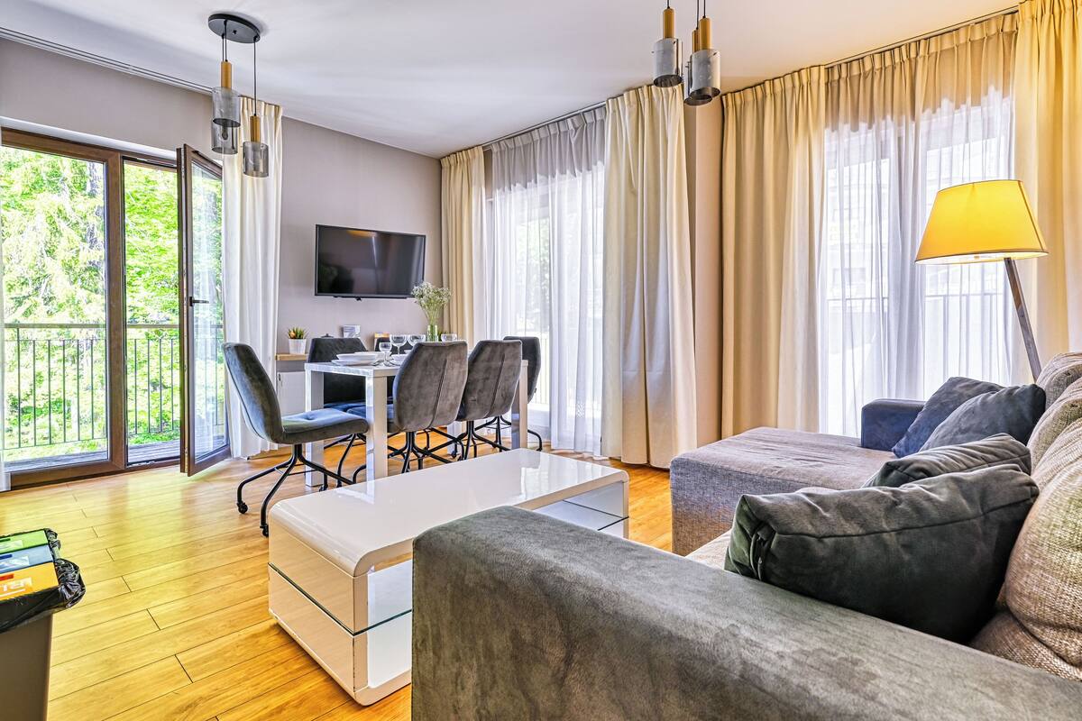 Una sala de estar moderna con un sofá, una mesa de centro, un televisor y un comedor con sillas y una mesa.