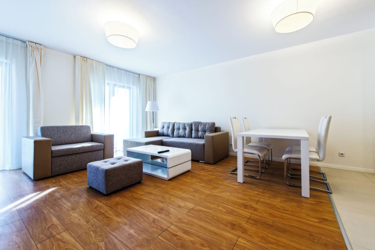 Una sala moderna con sofá, reposapiés, mesa de centro y comedor con sillas.