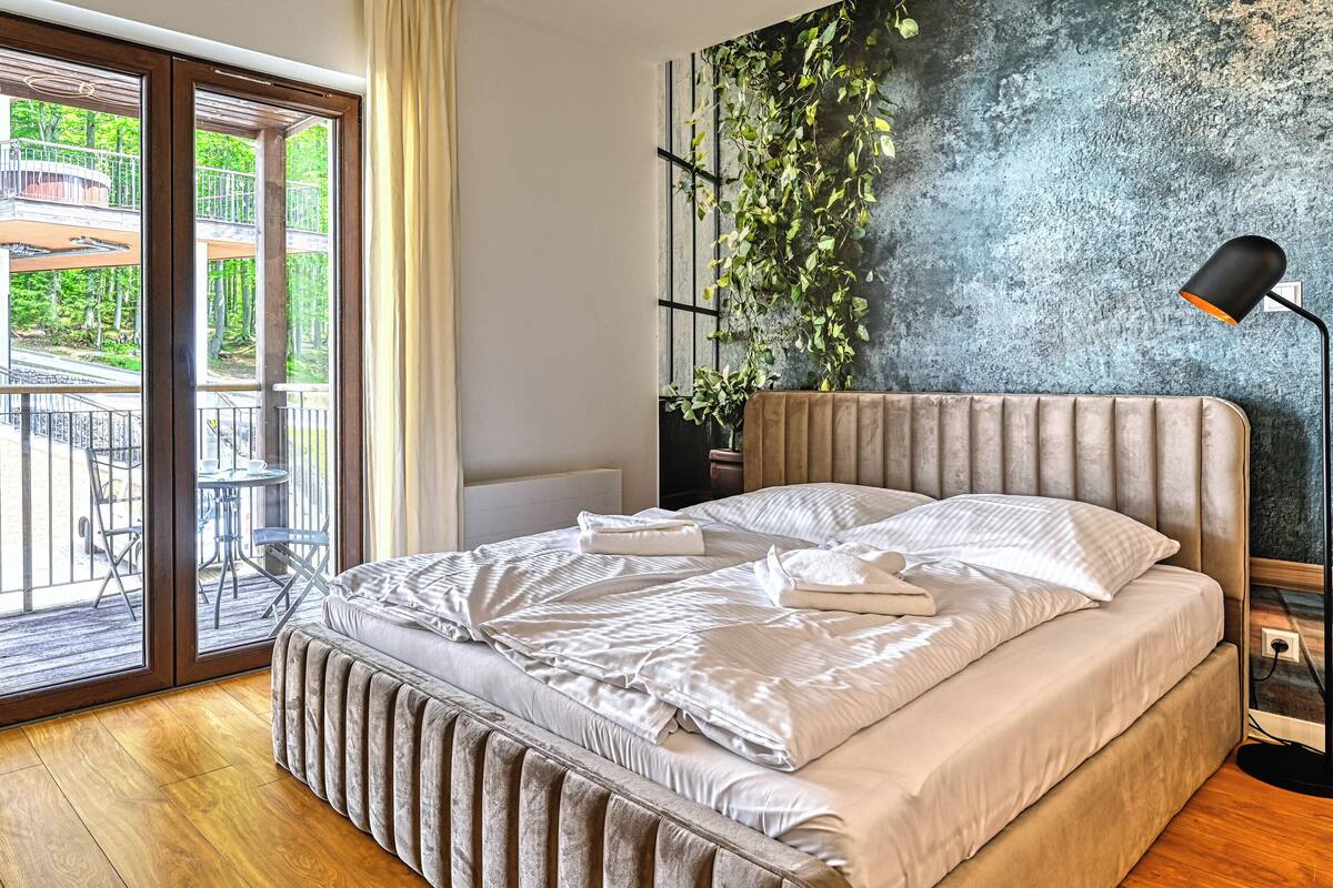 Un dormitorio con cama, vista a un balcón y una planta en la pared.