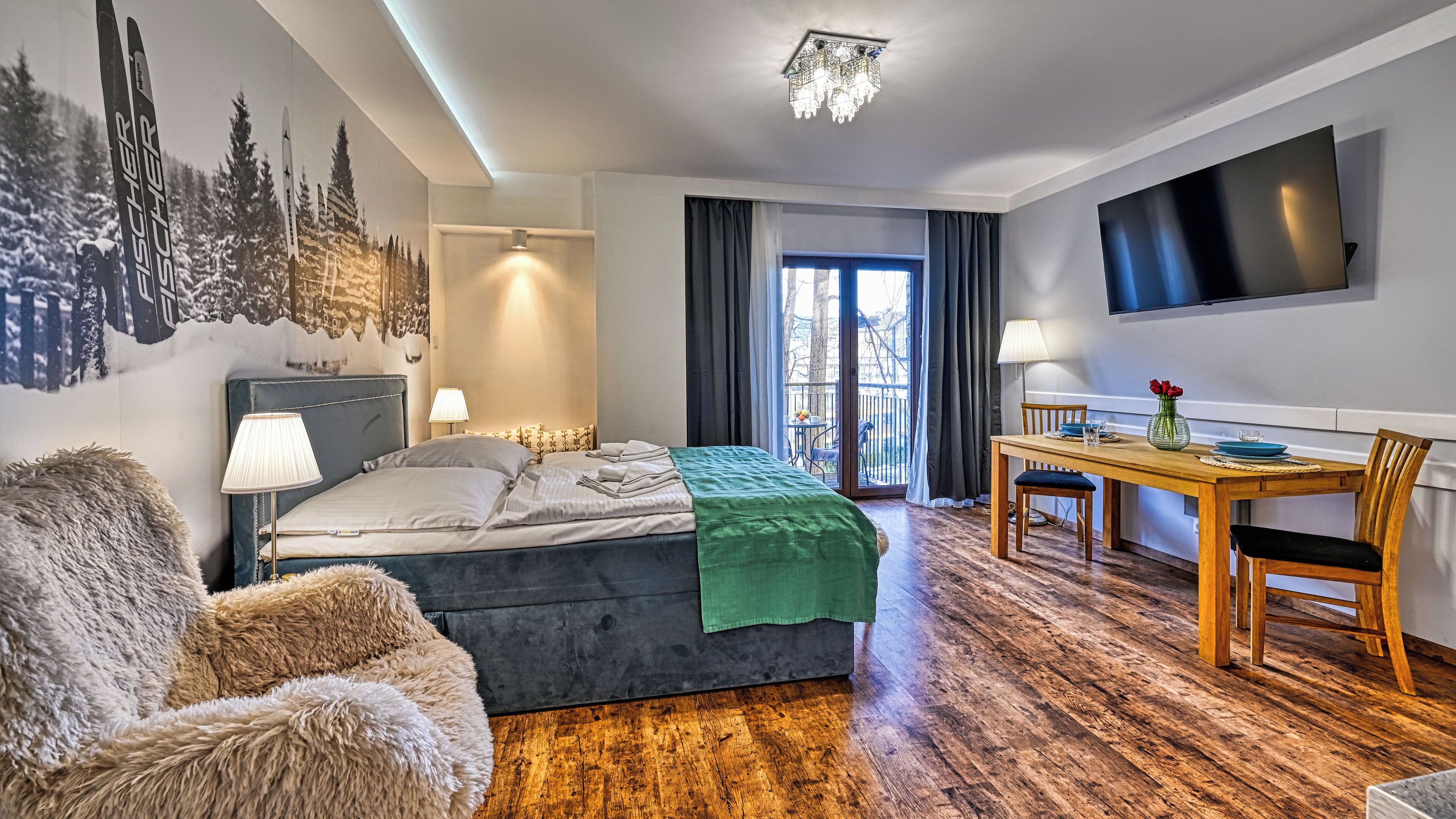 Una habitación de hotel moderna con cama, sillón, mesa y televisor.