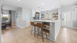 Una cocina moderna con una isla central, taburetes de bar y electrodomésticos integrados.