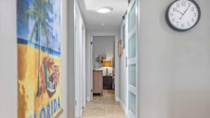 Un pasillo con un reloj, una puerta con paneles de vidrio esmerilado y una pared con un cartel de temática de Florida.