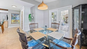 Un comedor con mesa de vidrio, individuales tejidos y sillas de mimbre.