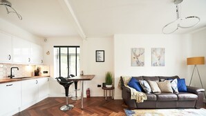 En moderne stue med en brun lædersofa, et sofabord og et spiseområde med en sort stol og et hvidt skab.