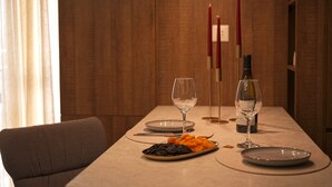 A dining table set with plates, a wine bottle, and glasses, with a candle and a vase in the background. - Designer Apartment Steps Away from Main Attractions (Yerevan)