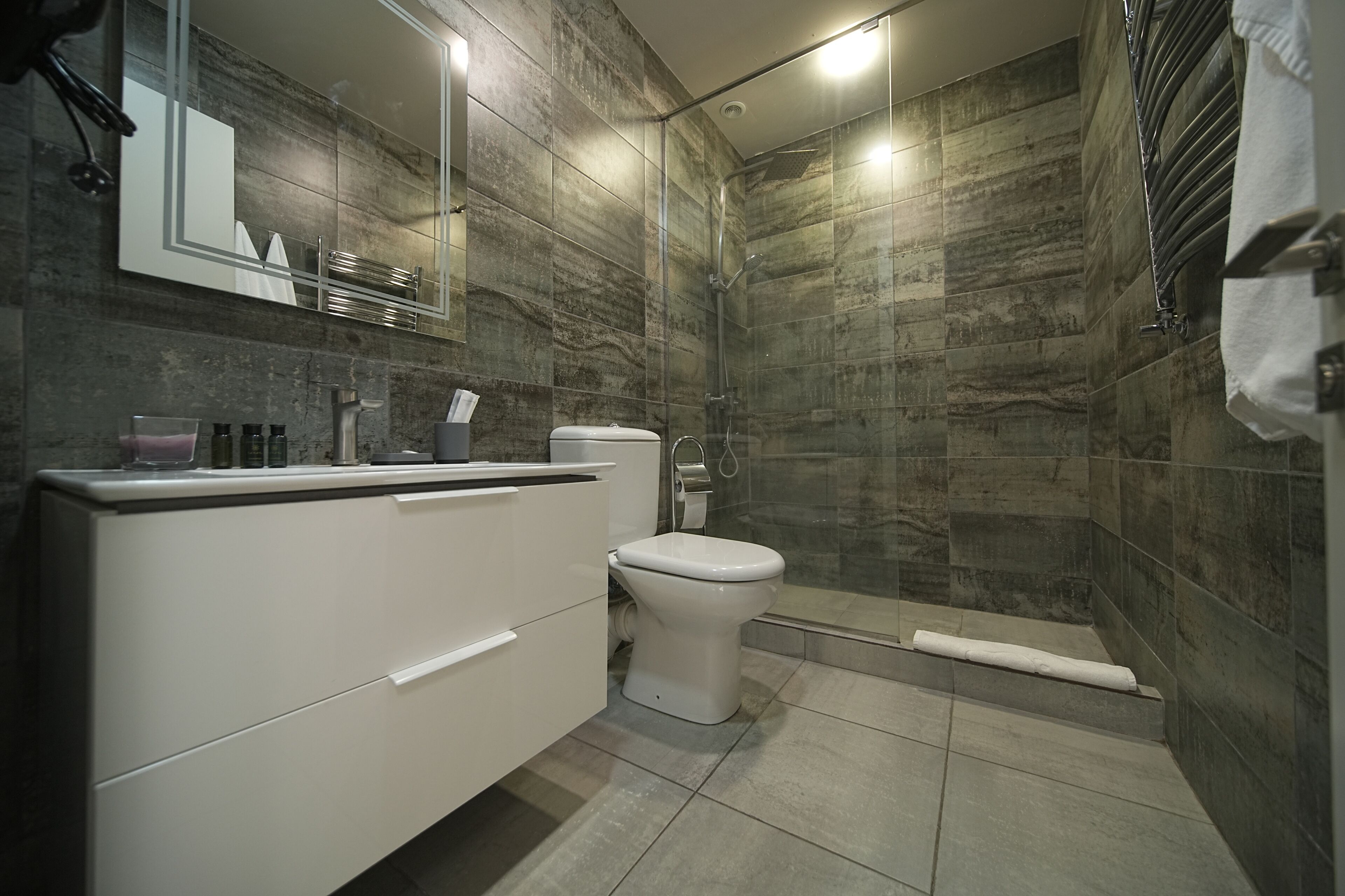 Un baño moderno con tocador blanco, inodoro y zona de ducha.