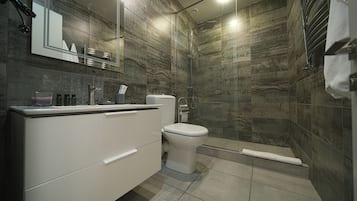 Un baño moderno con tocador blanco, inodoro y zona de ducha.