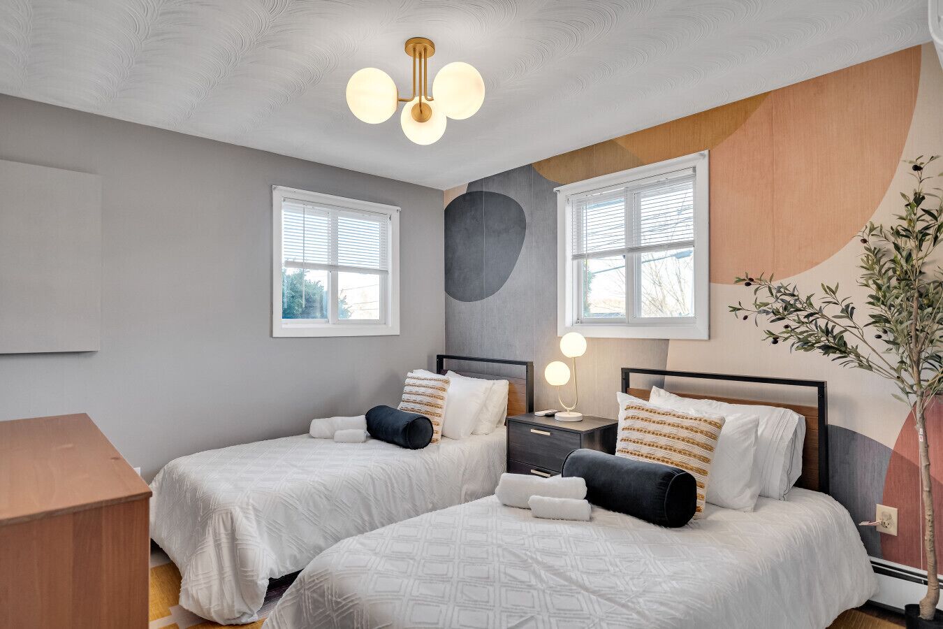 A double room with two beds, a bedside table with a lamp, and a large window.