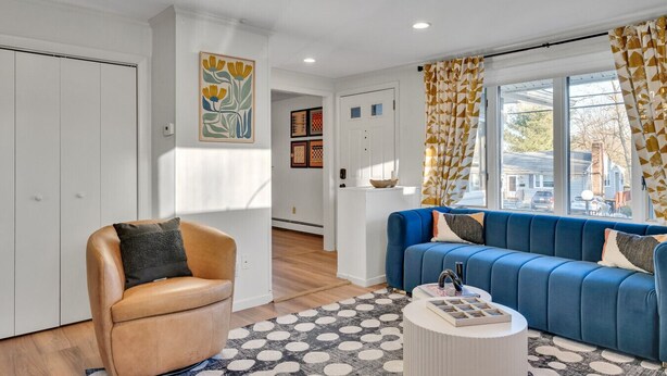 A modern living room with a blue sofa, a leather armchair, and a patterned rug. - Luxury Boston Ranch –Sleeps 8|Pet+|Heated pool (Framingham)