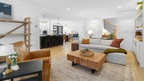 Een moderne woonkamer met een bank, salontafel en een eethoek op de achtergrond.