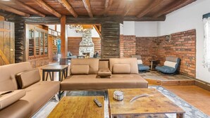 Un salon chaleureux avec un grand canapé beige, une table basse en bois et une cheminée en pierre.