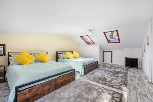 A bedroom with two beds, a skylight, and a sloped ceiling.