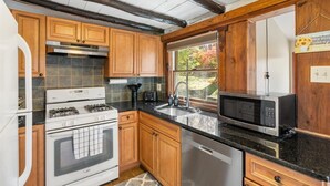 Une cuisine avec des meubles en bois, une cuisinière à gaz, un four à micro-ondes et un lave-vaisselle.