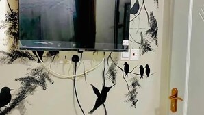 Un mur orné d’un téléviseur fixé au mur et de décorations murales sur le thème des oiseaux.