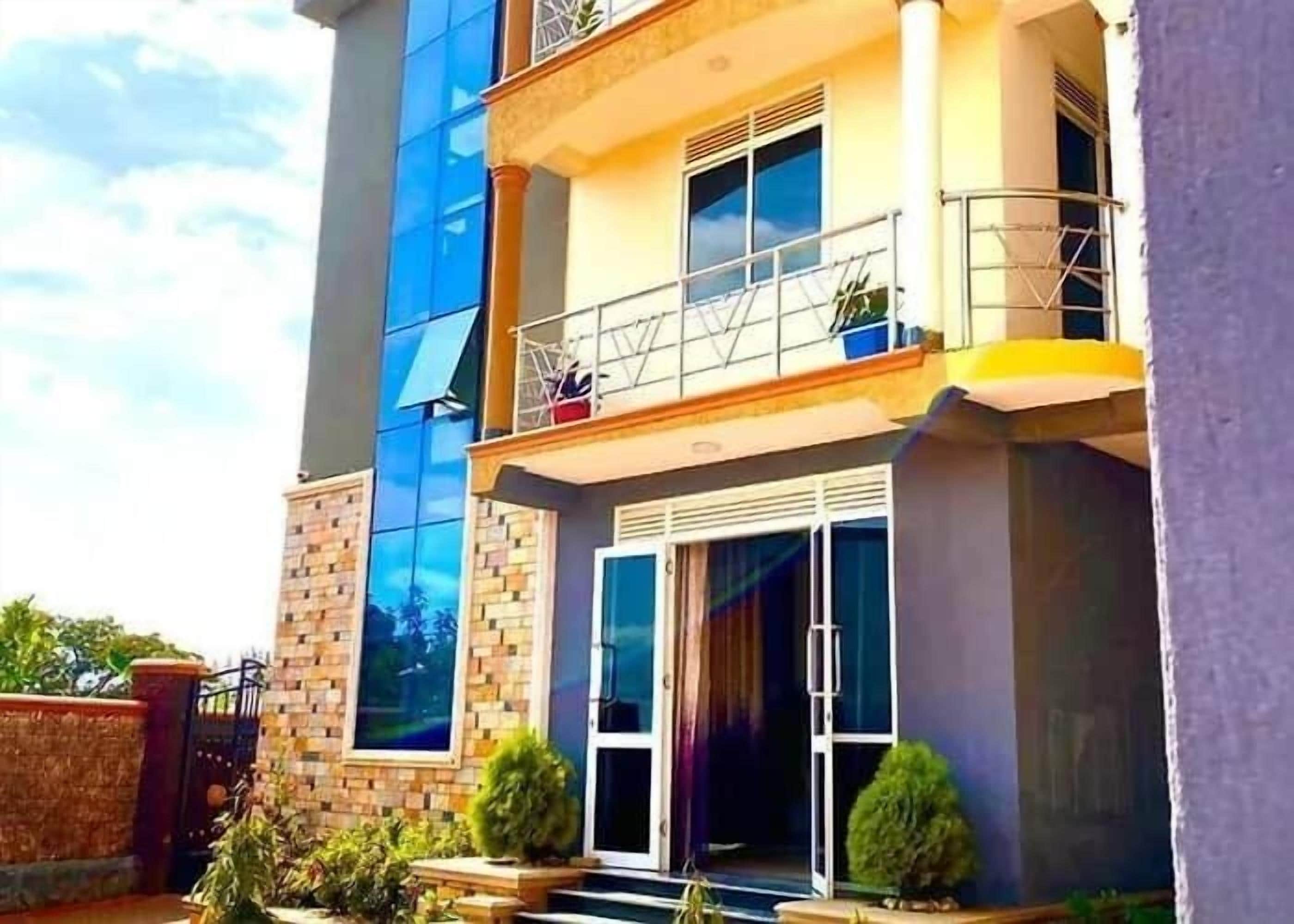 Un edificio moderno con fachada de vidrio, un balcón con barandilla metálica y un acceso con portón.