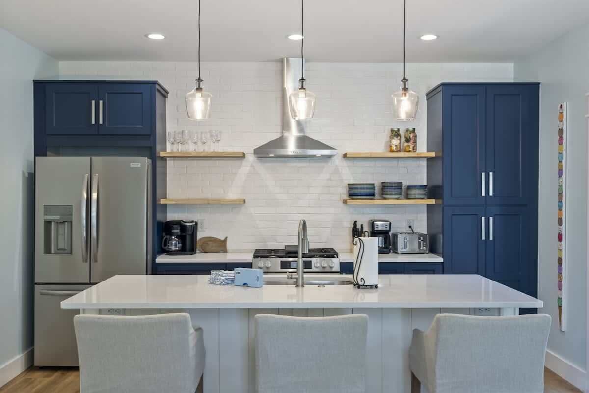 Una cocina moderna con una isla central, electrodomésticos de acero inoxidable y armarios azules.