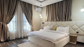 Ein modernes Hotelzimmer mit einem großen Bett, einem Kopfteil mit Rautenmuster und Holzboden.