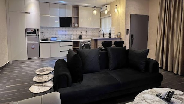 Ein modernes Wohnzimmer mit einer schwarzen Couch, einem Couchtisch und einem Essbereich mit einem kleinen Tisch und Stühlen.