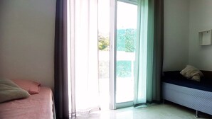 Een kamer met een bed, een slaapbank en een schuifdeur naar een balkon.