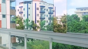 Een modern gebouw met balkons en een glazen hekwerk met uitzicht op groen.
