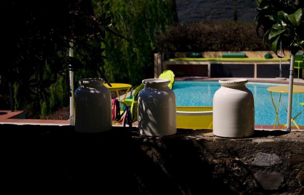 Zona junto a la piscina con tres macetas blancas de cerámica y una silla amarilla.