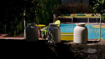 A poolside area with three white ceramic pots and a yellow chair.