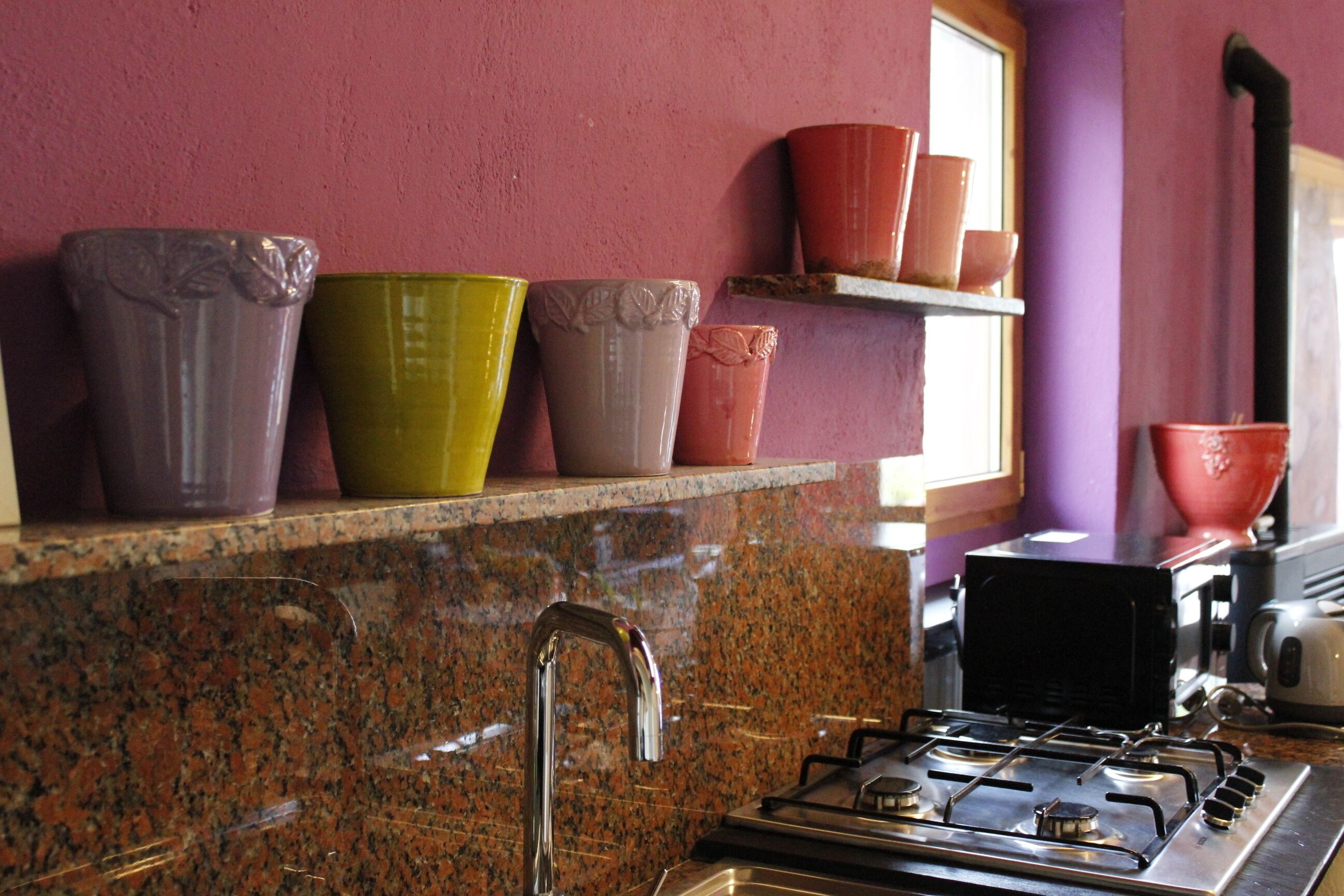 A kitchen with granite countertops, a gas stove, and a window with a view of the outside.