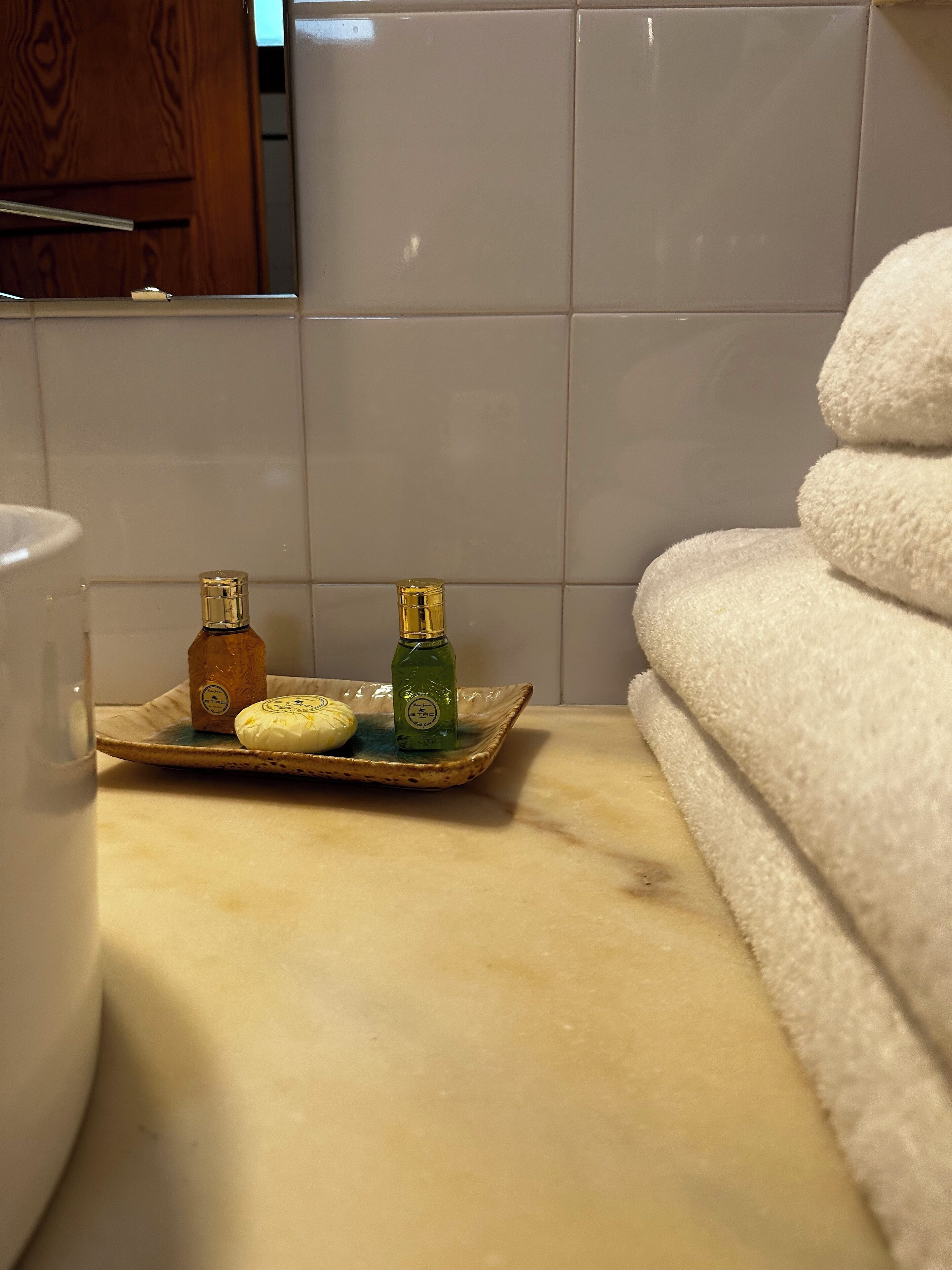 Une salle de bain avec un comptoir en marbre, une serviette blanche et deux flacons de savon liquide posés sur un plateau en céramique.