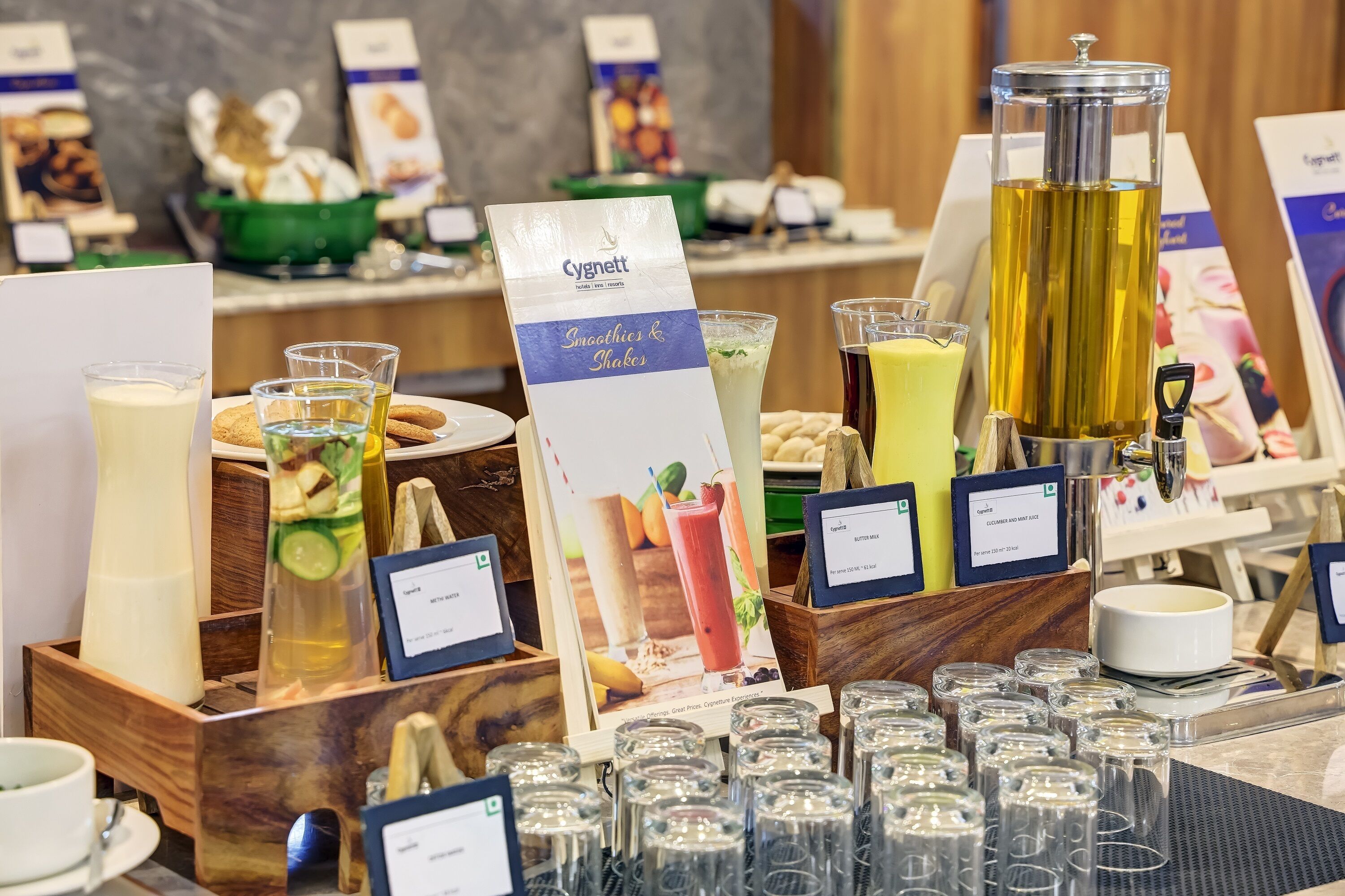 Un buffet de petit-déjeuner proposant une variété d’aliments et de boissons, notamment un stand de smoothies et de boissons rafraîchissantes de la marque Cygnet.