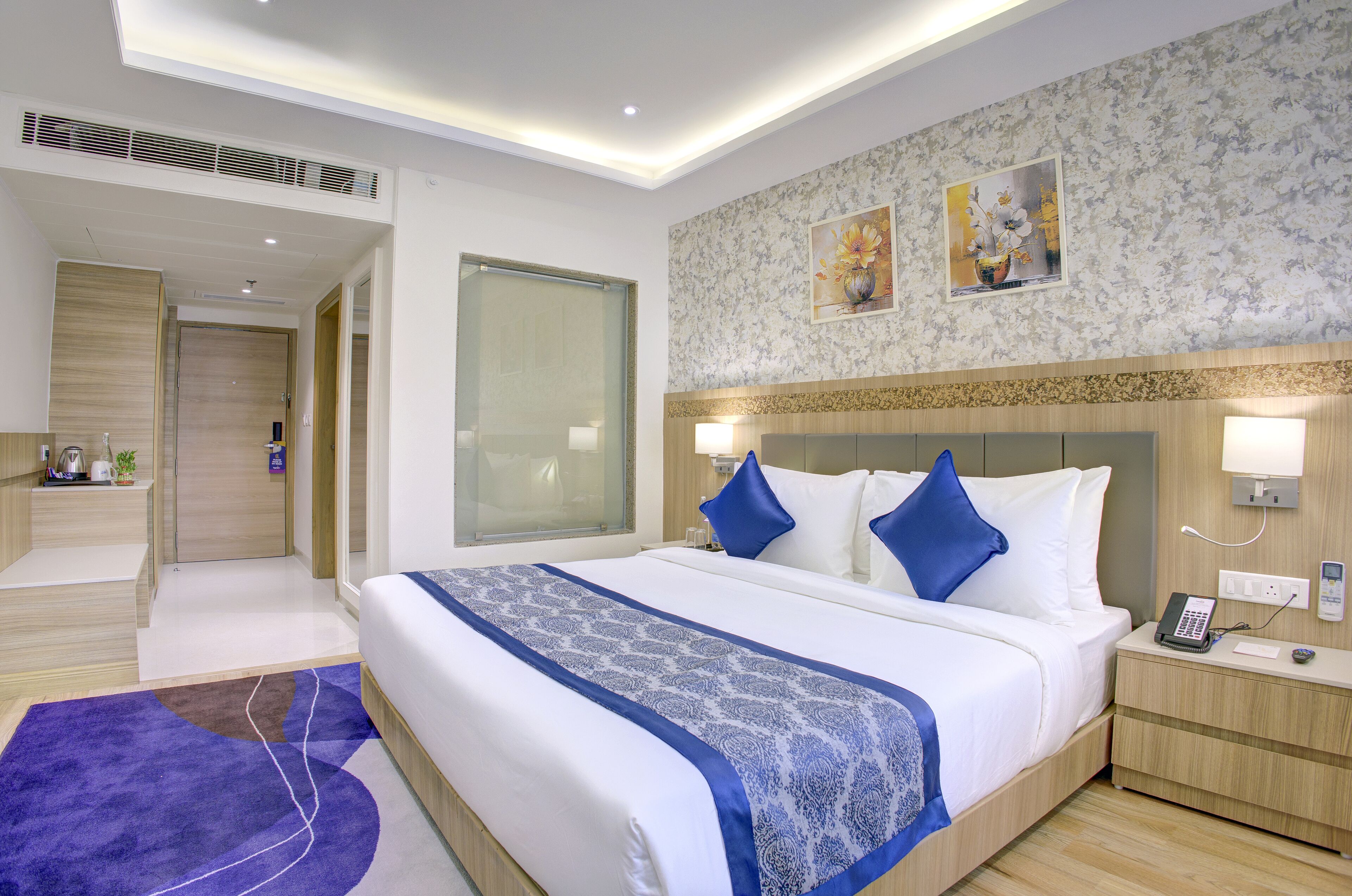 A modern hotel room with a large bed, bedside tables, a desk, and a shower area.