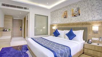 A modern hotel room with a large bed, bedside tables, a desk, and a shower area.