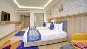 Une chambre d’hôtel avec deux lits, un canapé, un panier de fruits et une petite table.