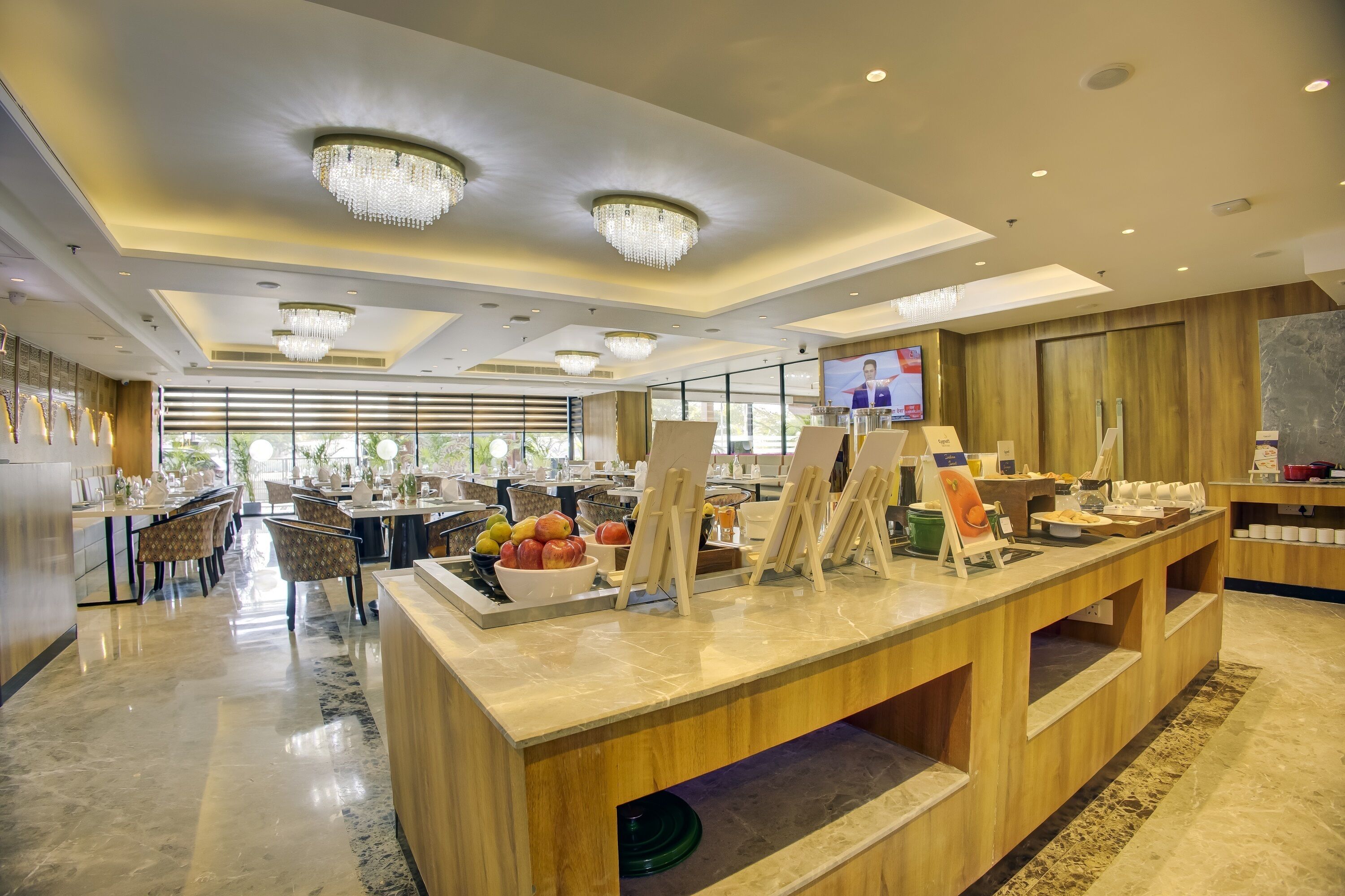 Un hall d’hôtel moderne avec un comptoir d’accueil en marbre, des éléments décoratifs en bois et des lustres.