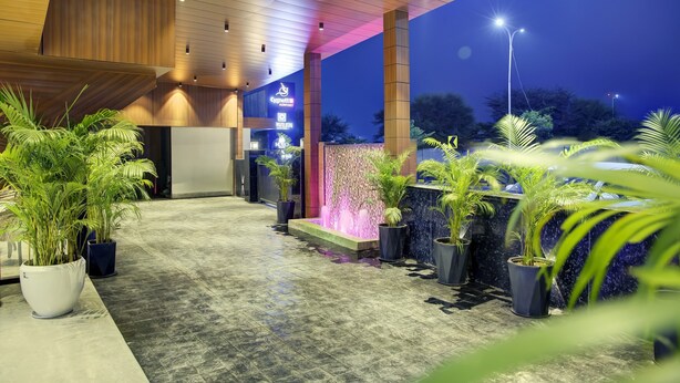 Une entrée d'hôtel moderne avec un plafond en bois, un panneau lumineux au néon et un élément décoratif aquatique.