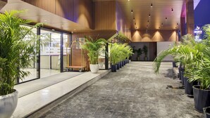 Un hall d’entrée spacieux, doté d’un sol en marbre poli, de lambris en bois sur les murs et d ’une rangée de plantes en pot le long du passage.